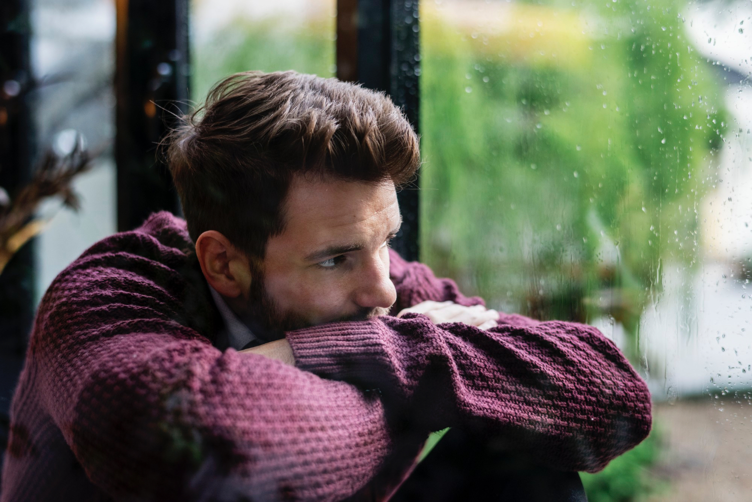 peur de l’abandon dans les relations Homme pensif regardant par la fenêtre, évoquant la peur de l’abandon et la solitude émotionnelle