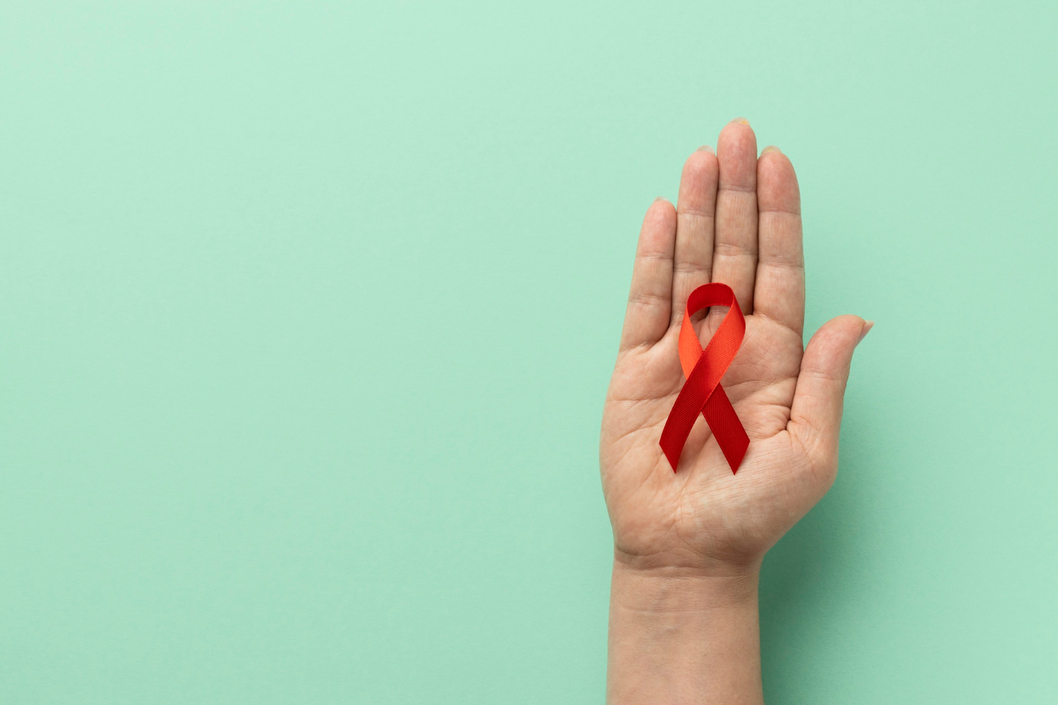 VIH : ruban rouge, symbole de sensibilisation et de soutien Main tenant un ruban rouge, symbole de la lutte contre le VIH et du soutien aux personnes vivant avec le VIH.